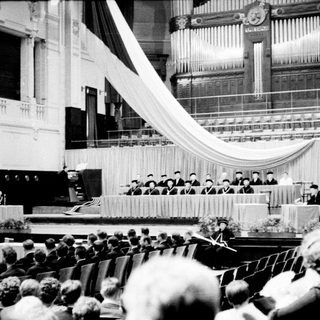 Formal ceremony with speakers and audience in a hall.