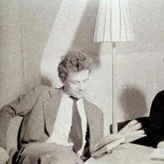 Man and woman sit reading, next to a lamp.