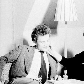 Man and woman seated, appearing to discuss something intently.