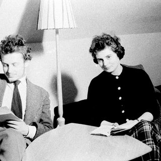 Two people reading books while seated on a couch.