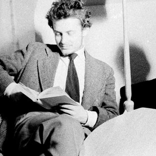 Two people reading books while seated on a couch.