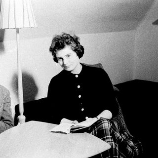 Two people reading books while seated on a couch.
