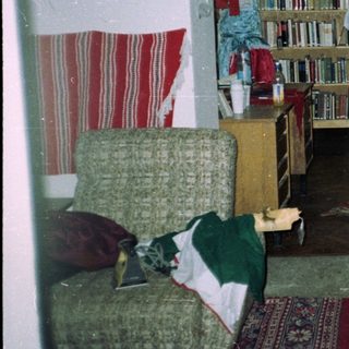 People in traditional dress stand near bookshelves in a room.
