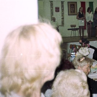 People gather in a hall with a small stage.