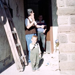 A child stands near a doorway with two men.