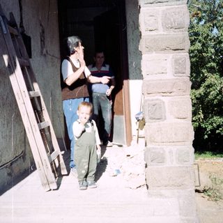 A child stands near a doorway with two men.