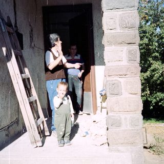 A child stands near a doorway with two men.