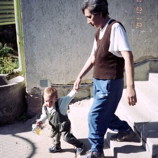 Man walks down stairs, assisting a toddler.