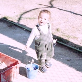 Young boy stands near construction materials in a yard.