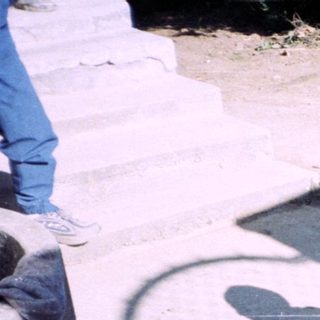 Young boy stands near construction materials in a yard.