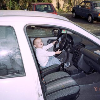 Young boy sits in a car, pretending to drive.