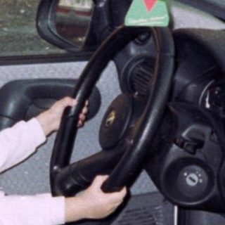 Young boy sits in a car, pretending to drive.