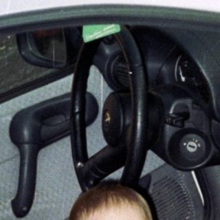 Boy crawls inside a white car, appearing playful.