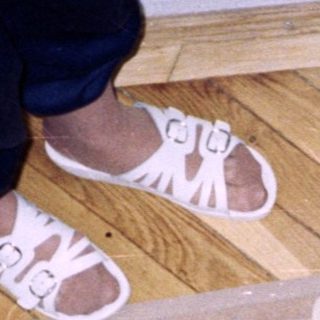 Infant standing on patterned rug, viewed from above.