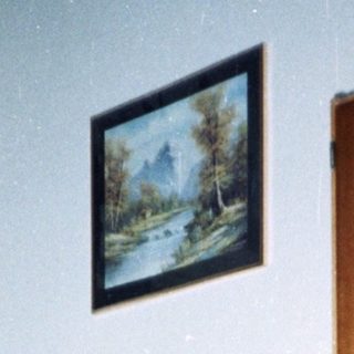 Young child sits near an adult in a patterned room.