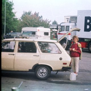 Boy stands next to car, truck with "BUSCH" logo.