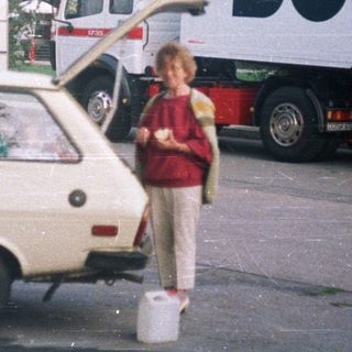 Boy stands next to car, truck with "BUSCH" logo.