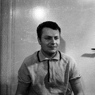 Man in a polo shirt stands in front of a door.