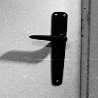 Man in a polo shirt stands in front of a door.