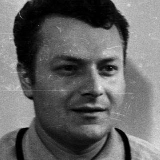 Man in a polo shirt stands in front of a door.