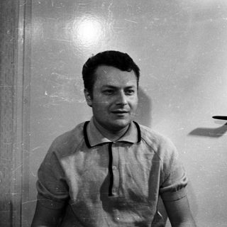 Man in a polo shirt stands in front of a door.