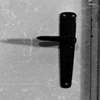 Man in polo shirt stands near a door.