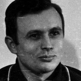 Man in polo shirt stands near a door.