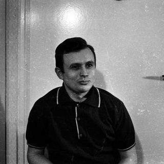 Man in polo shirt stands near a door.