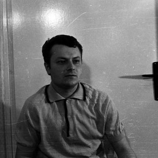 Man sits near a door, his shadow visible.