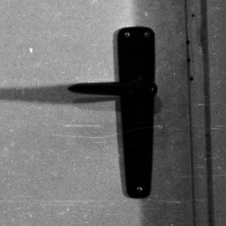 Man sits near a door, his shadow visible.