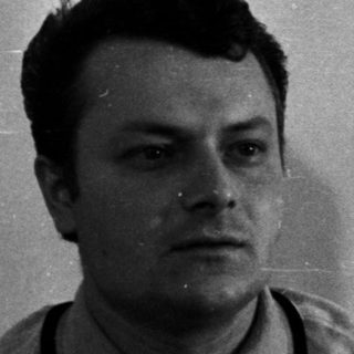 Man sits near a door, his shadow visible.