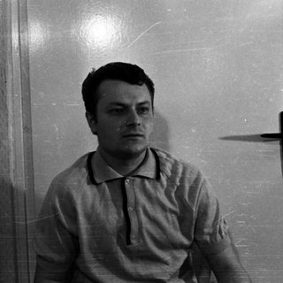Man sits near a door, his shadow visible.