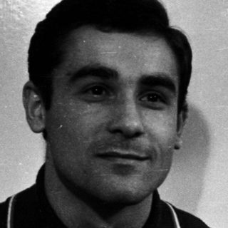 Black and white portrait of a man standing near a door.