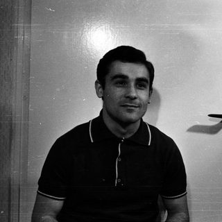 Black and white portrait of a man standing near a door.
