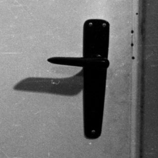 Man in polo shirt stands in front of a door.
