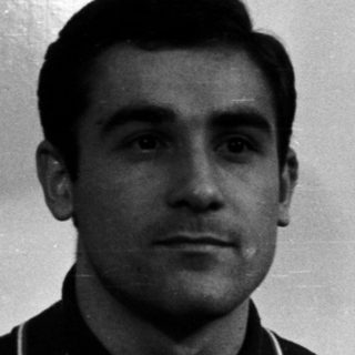 Man in polo shirt stands in front of a door.