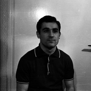 Man in polo shirt stands in front of a door.