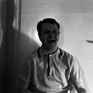 Man with a wide, open mouth against a door.