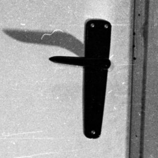 Man with a wide, open mouth against a door.