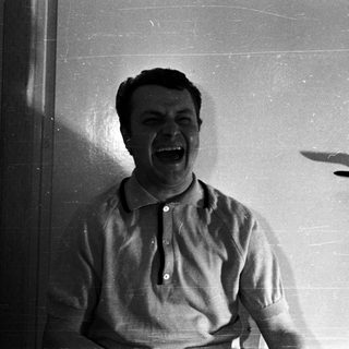 Man with a wide, open mouth against a door.