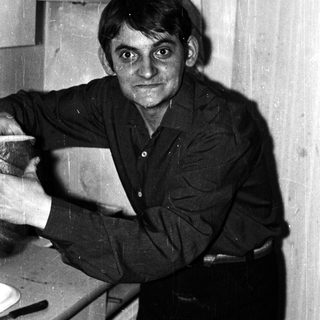 Here's a brief summary of the image: Man in a dark shirt sits at a table.
