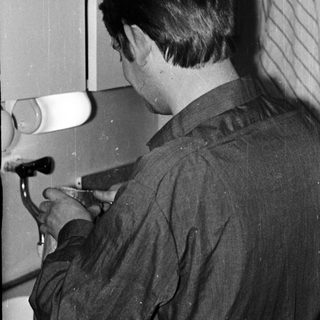 Man working at a workbench with tools and machinery.