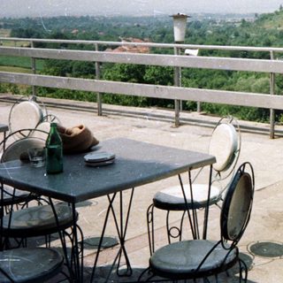 Man stands on a rooftop overlooking a hillside landscape.