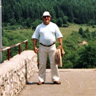 Man stands on a platform overlooking a forested valley.