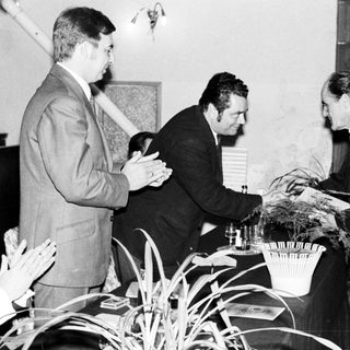 Men present a plant, appearing to be an award ceremony.