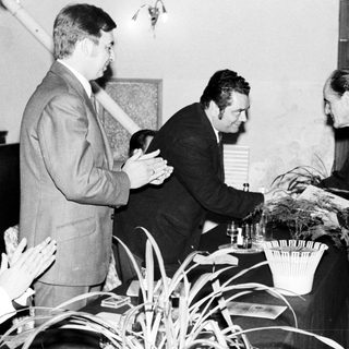 Men present a plant, appearing to be an award ceremony.