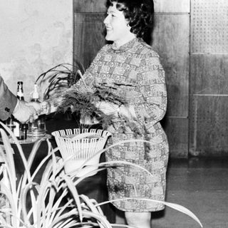 Man serves drinks to a woman in a patterned dress.
