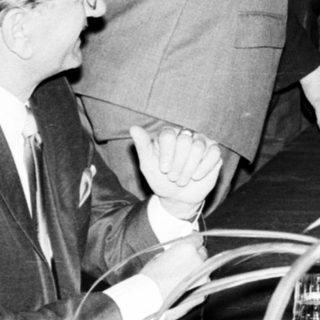 Man serves drinks to a woman in a patterned dress.