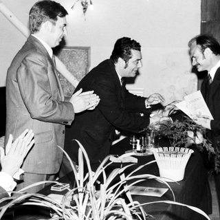 Men in suits appear to be presenting a document.