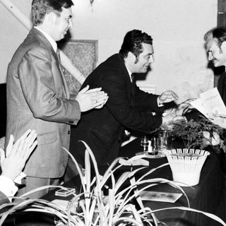 Men in suits appear to be presenting a document.